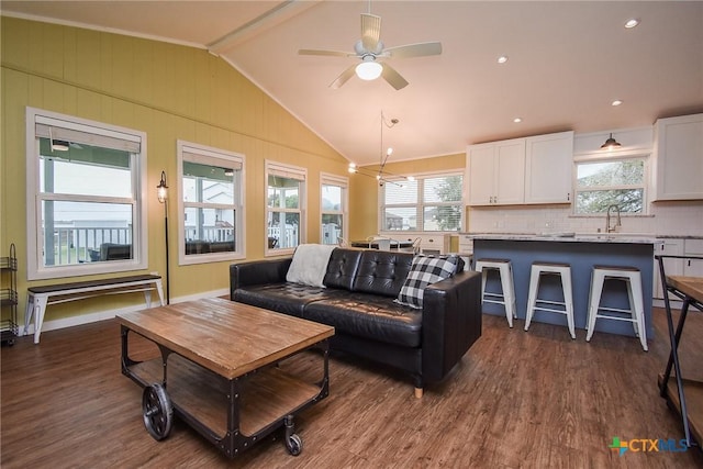 living room featuring dark hardwood / wood-style floors, ceiling fan, sink, and vaulted ceiling