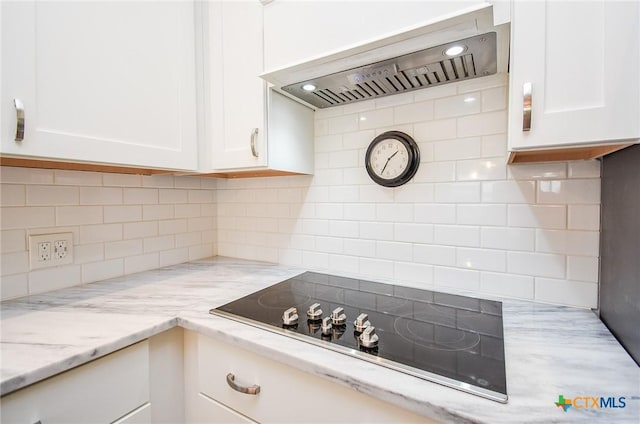 kitchen featuring decorative backsplash, white cabinetry, and wall chimney range hood