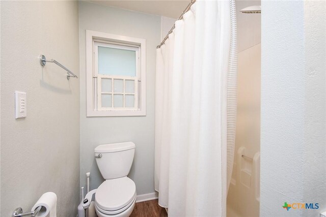 bathroom with a shower with curtain, wood-type flooring, and toilet