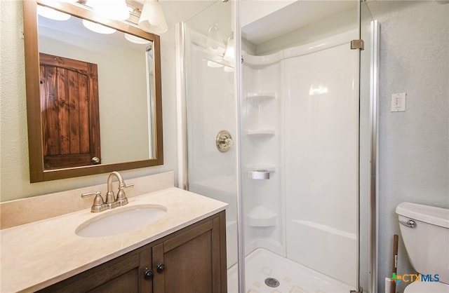 bathroom featuring vanity, toilet, and a shower with door