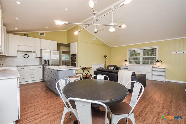 dining space featuring a notable chandelier, sink, vaulted ceiling, and hardwood / wood-style flooring