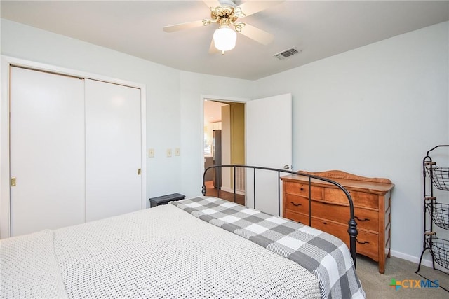 bedroom with carpet flooring, a closet, stainless steel refrigerator, and ceiling fan