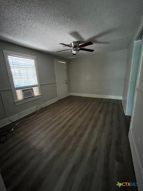 empty room featuring ceiling fan, dark hardwood / wood-style flooring, cooling unit, and a textured ceiling