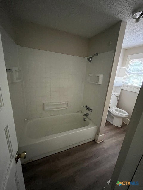 bathroom featuring hardwood / wood-style floors, tiled shower / bath, a textured ceiling, and toilet