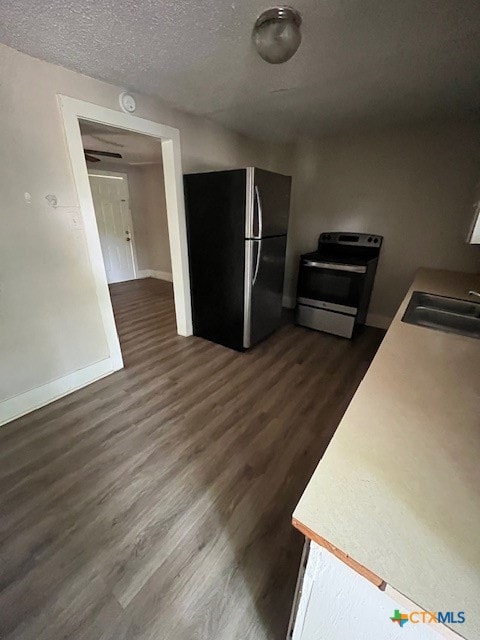 kitchen with a textured ceiling, sink, stainless steel appliances, and dark hardwood / wood-style floors