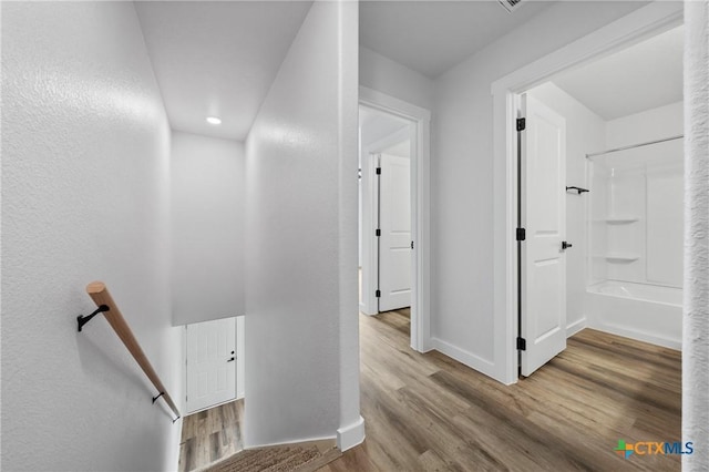 hall with baseboards, an upstairs landing, and wood finished floors