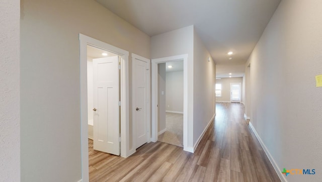 hall featuring recessed lighting, wood finished floors, and baseboards