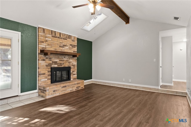 unfurnished living room featuring vaulted ceiling with skylight, a fireplace, wood finished floors, and visible vents