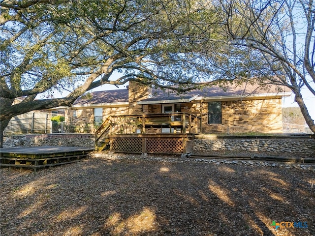 back of house with brick siding and a wooden deck