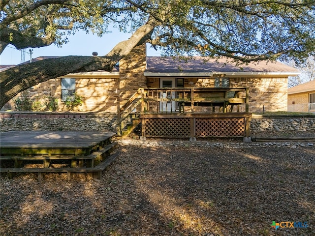 back of property featuring brick siding and a wooden deck