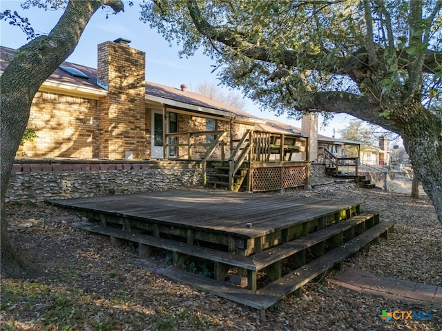 back of house with brick siding, a chimney, and a wooden deck