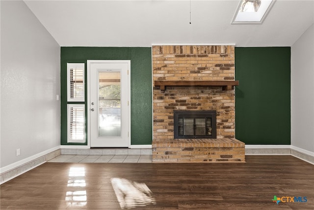 unfurnished living room featuring lofted ceiling, a fireplace, baseboards, and wood finished floors