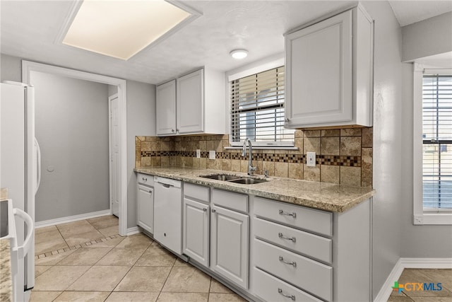 kitchen featuring white appliances, decorative backsplash, a sink, and a healthy amount of sunlight