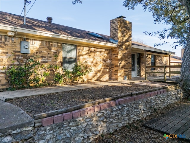 rear view of house featuring a chimney and brick siding