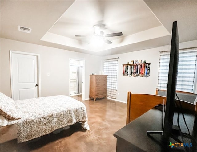 bedroom featuring a tray ceiling, concrete flooring, and ceiling fan