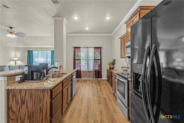 1703 Fossil Trl, Belton, TX 76513 - kitchen with appliances with stainless steel finishes, light wood-type flooring, brown cabinets, an island with sink, and ceiling fan