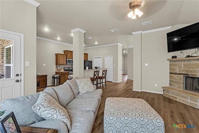 1703 Fossil Trl, Belton, TX 76513 - living area featuring dark wood-style floors, a ceiling fan, crown molding, decorative columns, and a stone fireplace