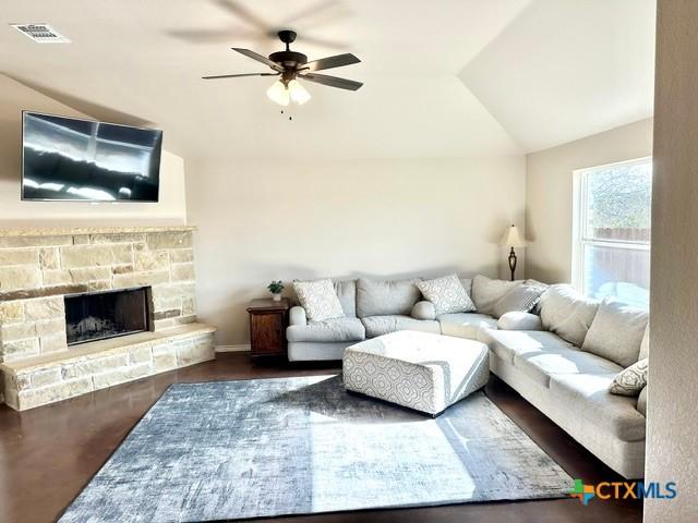 living room with ceiling fan, a fireplace, dark hardwood / wood-style flooring, and vaulted ceiling