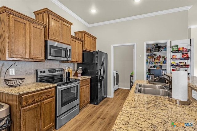 1703 Fossil Trl, Belton, TX 76513 - kitchen with stainless steel appliances, washer / dryer, crown molding, light wood-style flooring, and brown cabinetry