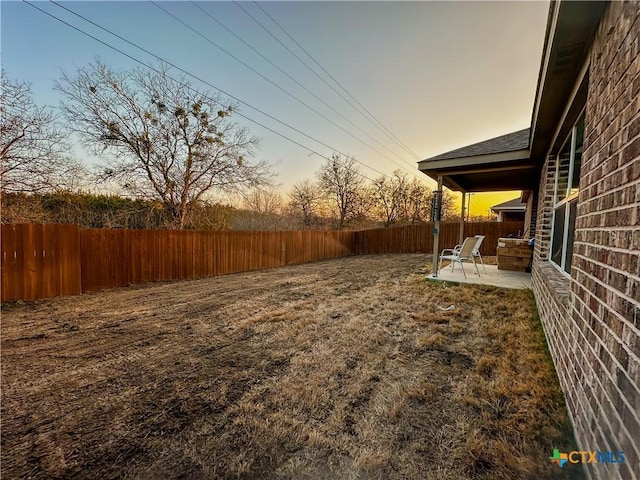 yard at dusk featuring a patio