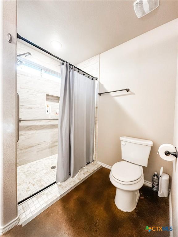 bathroom featuring a shower with curtain and toilet