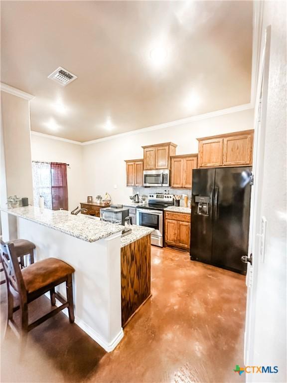 kitchen featuring sink, appliances with stainless steel finishes, light stone countertops, a kitchen bar, and kitchen peninsula