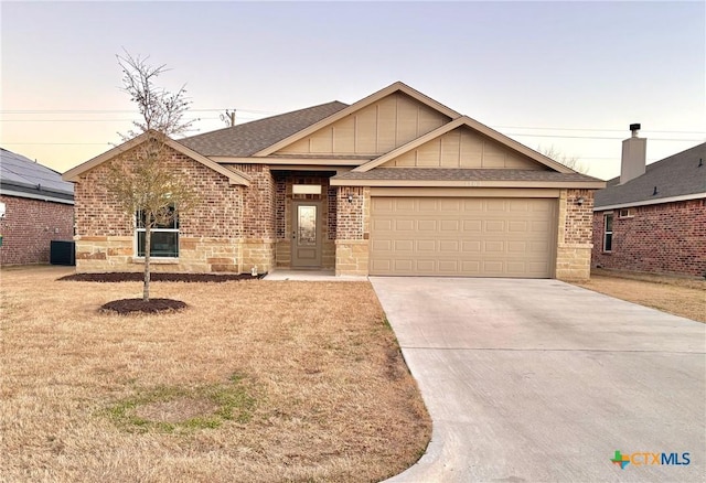 view of front of house with central AC unit, a garage, and a yard