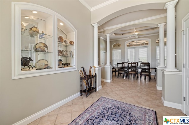 hall with ornate columns, light tile patterned floors, and ornamental molding