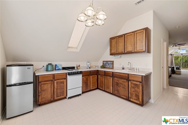 kitchen featuring stainless steel refrigerator, sink, lofted ceiling with skylight, ceiling fan with notable chandelier, and white range oven