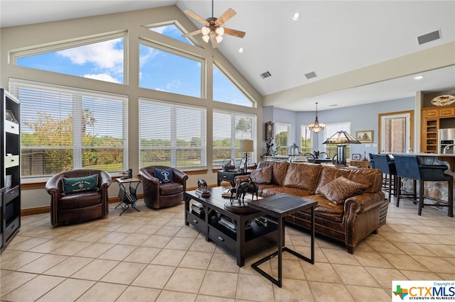 tiled living room with high vaulted ceiling and ceiling fan with notable chandelier