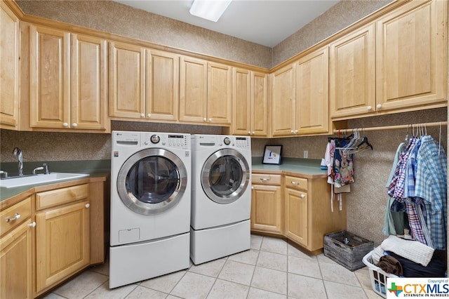 laundry room featuring cabinets, sink, light tile patterned floors, and separate washer and dryer