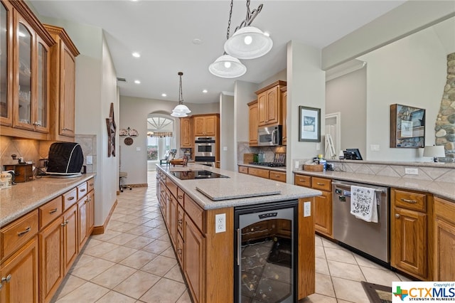 kitchen featuring stainless steel appliances, beverage cooler, an island with sink, and backsplash