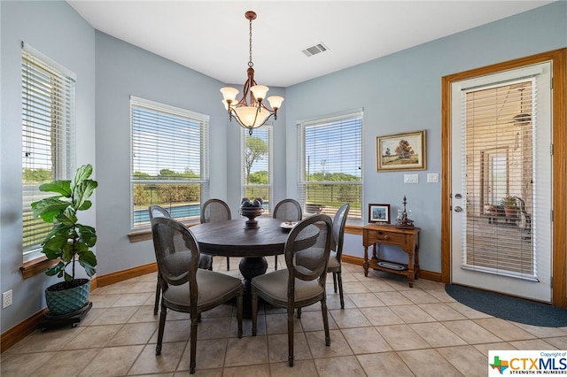 tiled dining room with an inviting chandelier