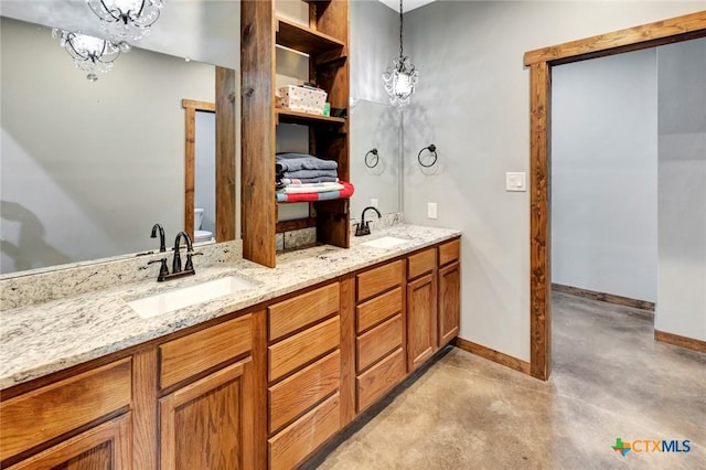 1622 Old Goliad Rd, Victoria, TX 77905 - bathroom featuring baseboards, concrete floors, toilet, double vanity, and a chandelier