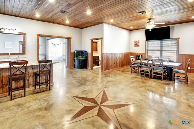 1622 Old Goliad Rd, Victoria, TX 77905 - dining area featuring a wainscoted wall, concrete floors, wooden walls, wood ceiling, and a ceiling fan