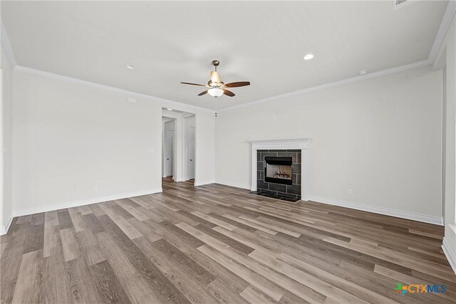 6402 Waggoner Ct, Temple, TX 76502 - unfurnished living room featuring ceiling fan, a tiled fireplace, light hardwood / wood-style flooring, and ornamental molding