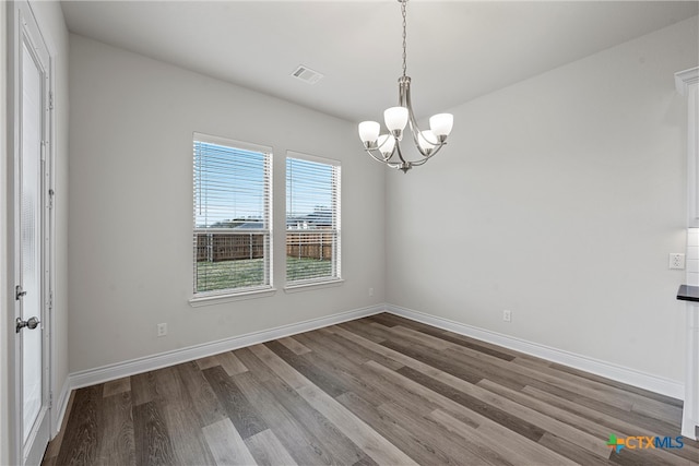 empty room with hardwood / wood-style floors and a notable chandelier