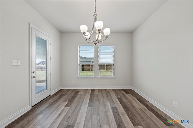 unfurnished dining area featuring an inviting chandelier and hardwood / wood-style floors