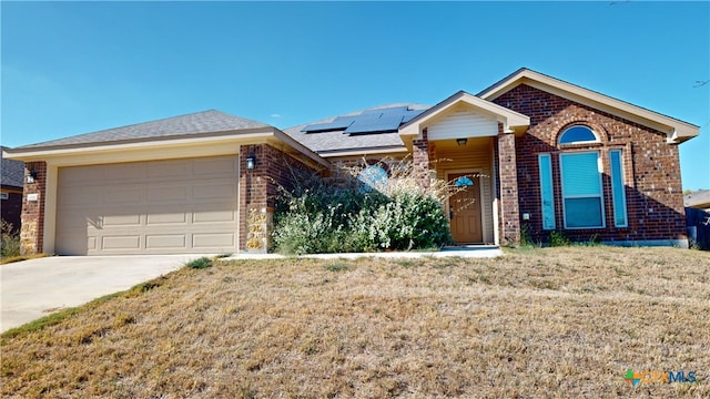 view of front facade featuring a garage, solar panels, and a front lawn