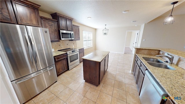 kitchen featuring sink, light stone countertops, decorative light fixtures, and stainless steel appliances