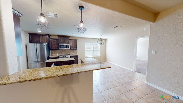 kitchen featuring tasteful backsplash, light stone counters, stainless steel appliances, decorative light fixtures, and dark brown cabinets