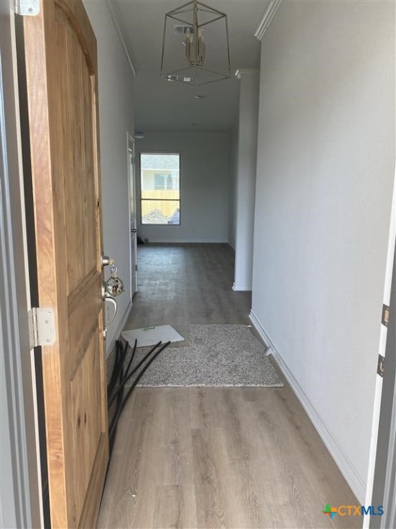 hall featuring baseboards, ornamental molding, and wood finished floors