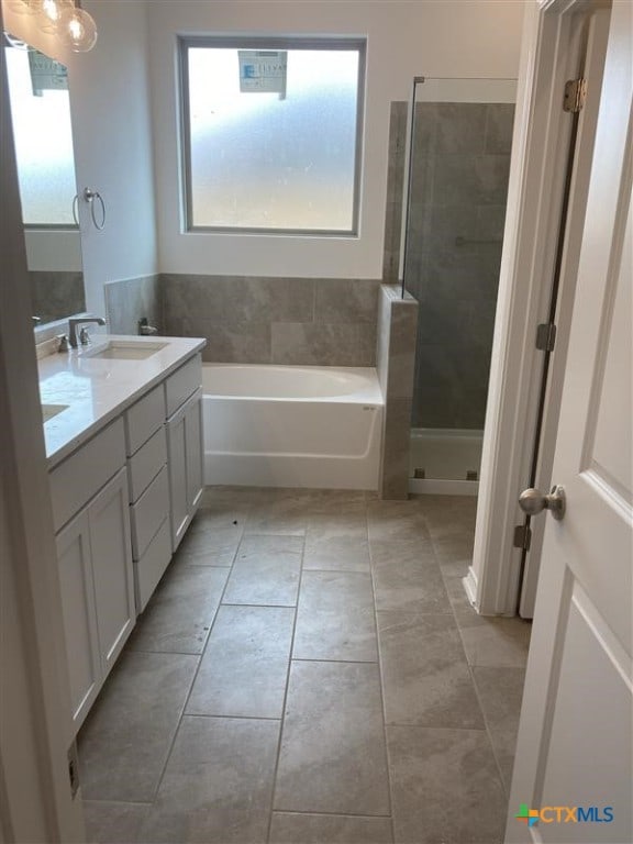 full bath featuring a garden tub, double vanity, a sink, tile patterned flooring, and tiled shower