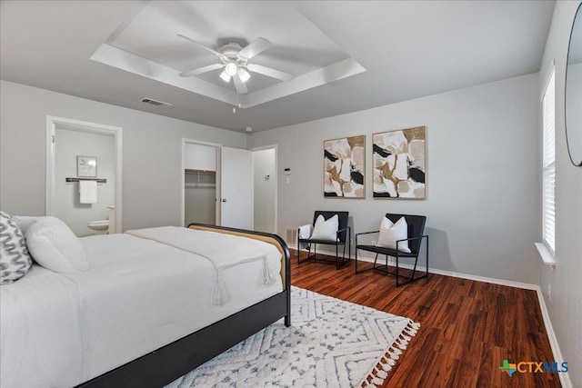 2102 Garrison Dr, Leander, TX 78641 - bedroom featuring a raised ceiling, wood finished floors, ensuite bath, and multiple windows