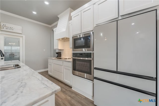 kitchen with freestanding refrigerator, white cabinets, stainless steel oven, a sink, and built in microwave