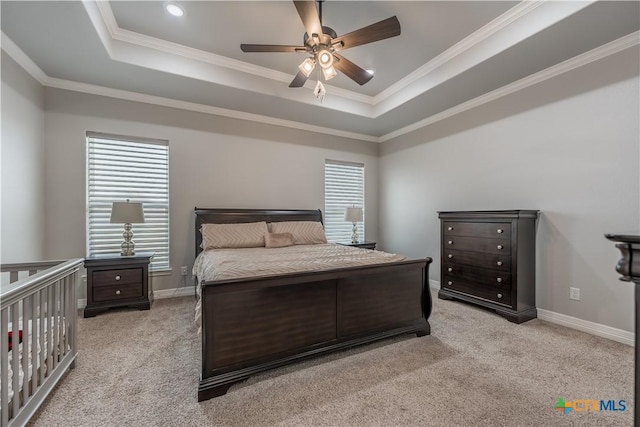 carpeted bedroom featuring ornamental molding, a tray ceiling, and multiple windows