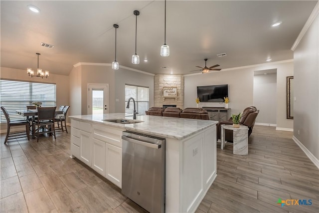 kitchen featuring an island with sink, stainless steel dishwasher, white cabinetry, a sink, and ceiling fan with notable chandelier