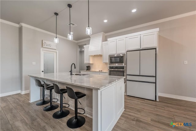 kitchen featuring white cabinets, stainless steel oven, a sink, built in microwave, and fridge