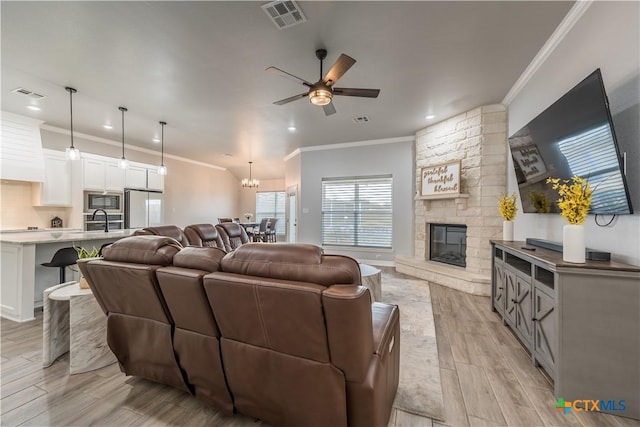 living area featuring ornamental molding, a stone fireplace, light wood-type flooring, and visible vents