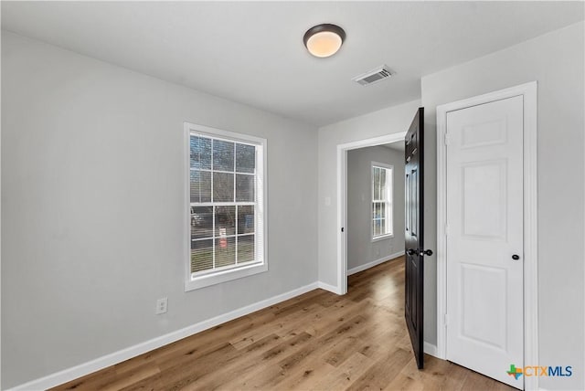 unfurnished room with visible vents, light wood-style floors, and baseboards